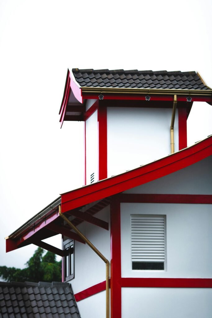 Exterior of a Japanese-inspired building with red and white accents and a tiled roof.